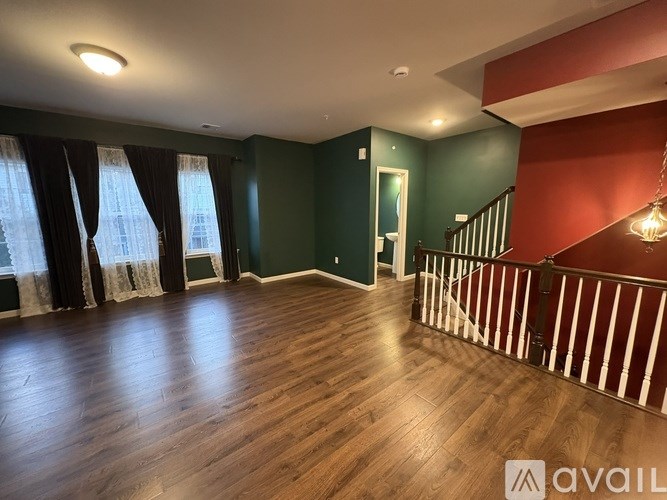 A room with wooden floors and a staircase with red walls.