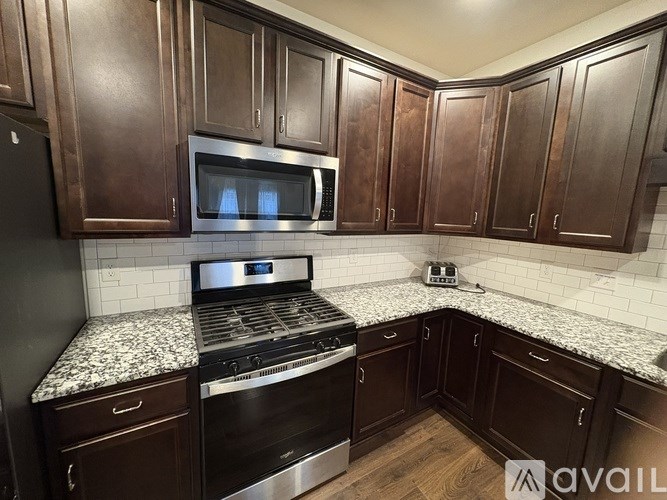 A kitchen with dark wood cabinets and a granite countertop.