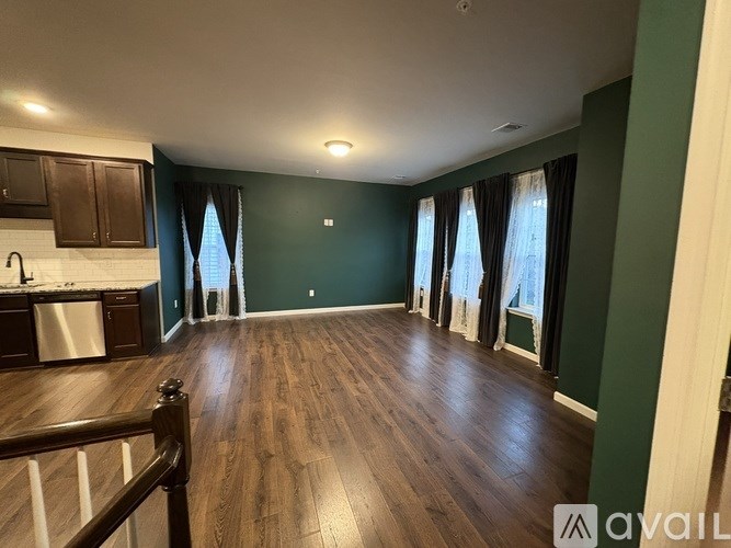 A spacious room with wood flooring and a kitchen area with a sink and cabinets.