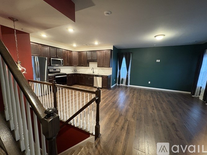 A spacious kitchen with dark green walls and wooden flooring.