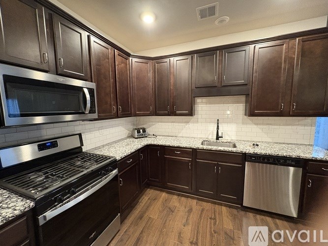 A kitchen with dark brown cabinets and stainless steel appliances.