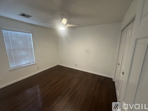 A room with wooden flooring and a window with blinds.