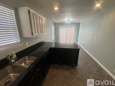A kitchen with black cabinets and a stainless steel sink.