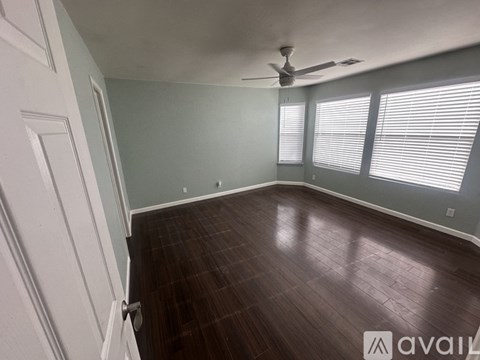 A room with a ceiling fan and wooden flooring.
