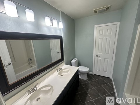 A bathroom with a toilet, sink, and mirror.