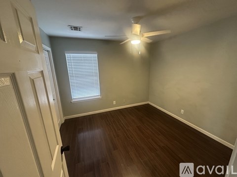 A room with a ceiling fan and a window with blinds.
