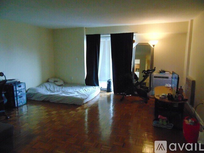 A bedroom with a bed, a desk, and a bicycle.