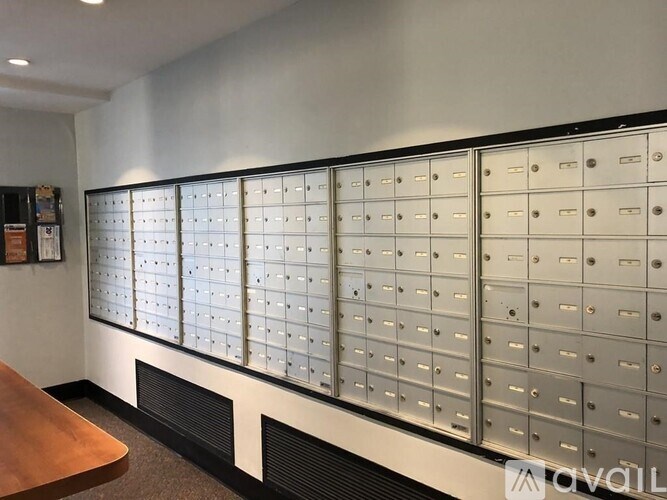 A row of metal mailboxes are lined up against a wall.