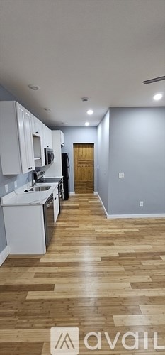 A kitchen with white cabinets and a wooden floor.