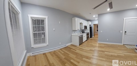 A kitchen area with wooden floors and a window with blinds.