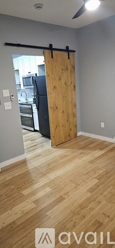 A room with a wooden floor and a sliding door leading to a kitchen.