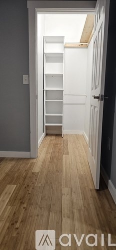 A hallway with wooden floors and a white door.