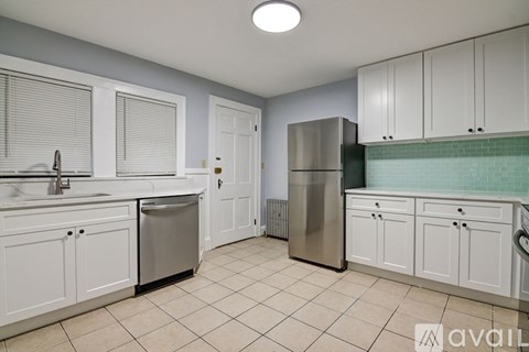 A kitchen with white cabinets and a stainless steel refrigerator.