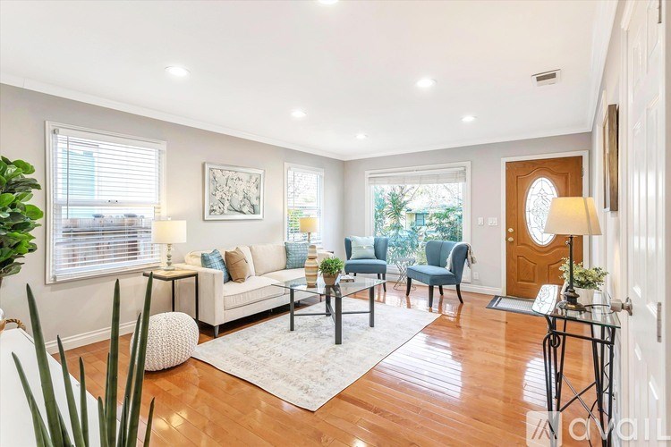 A living room with a white couch, a blue chair, and a white rug.