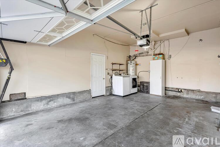 A large, empty room with a white door and a white refrigerator.