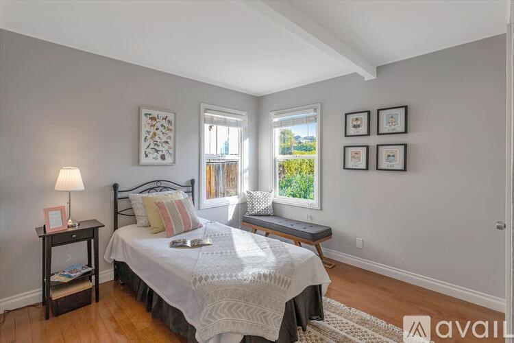 A bedroom with a bed, nightstand, and window.