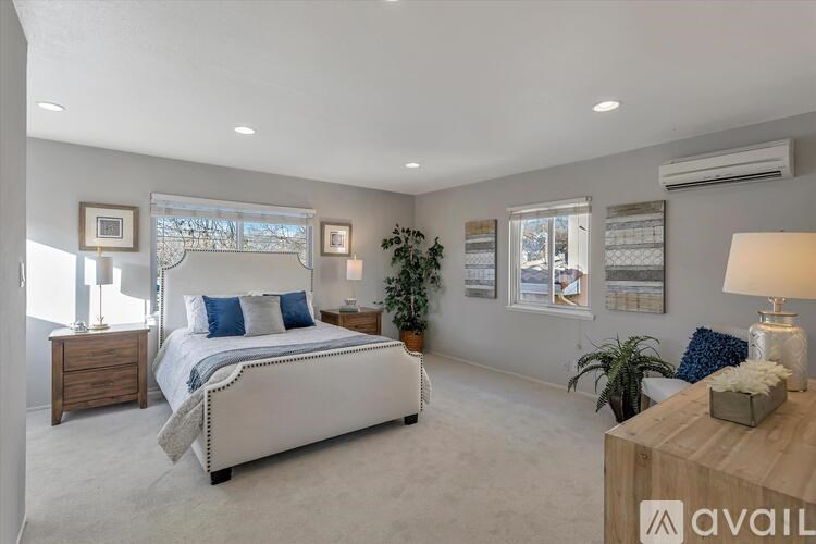 A bedroom with a large bed, a wooden nightstand, and a lamp on a table.