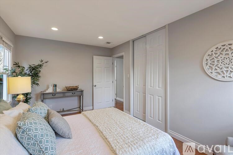 A bedroom with a bed, nightstand, and a wall hanging.