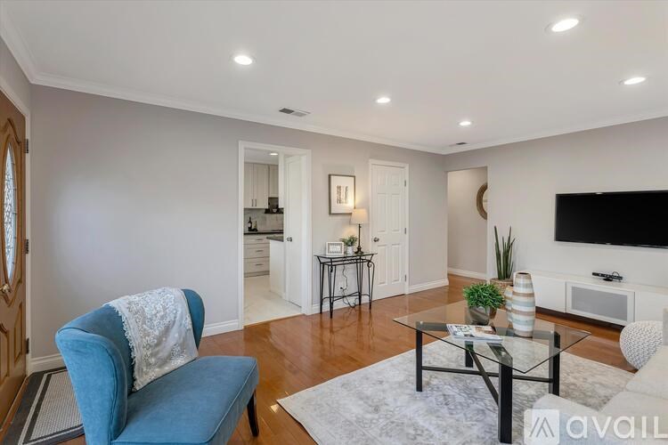 A living room with a blue chair and a glass coffee table.