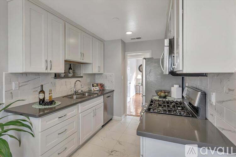 A kitchen with white cabinets and a marble countertop.