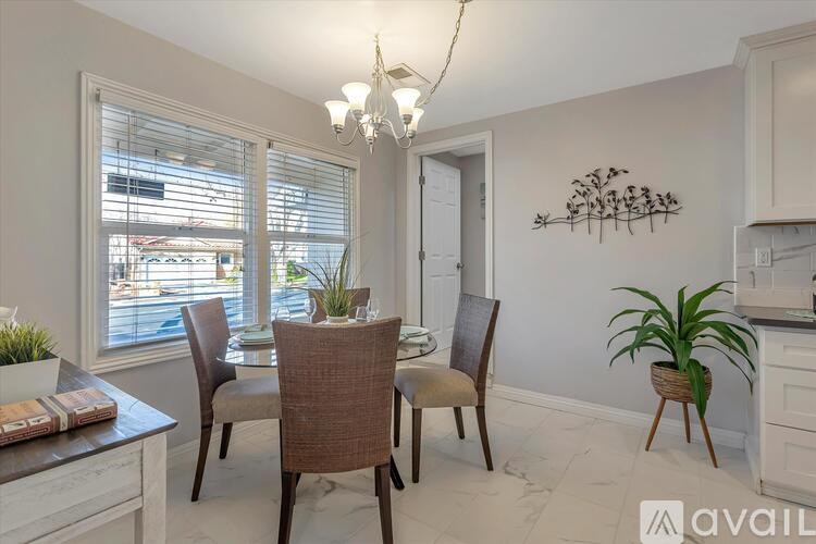 A dining room with a table set for two and a chandelier hanging from the ceiling.