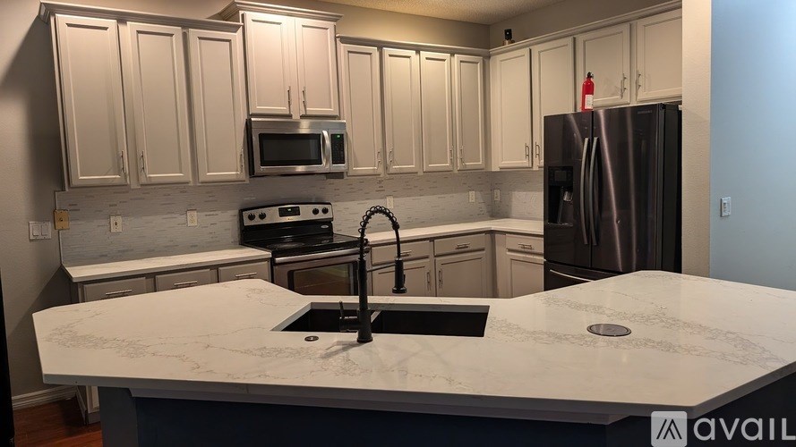 A kitchen with a marble countertop and stainless steel appliances.