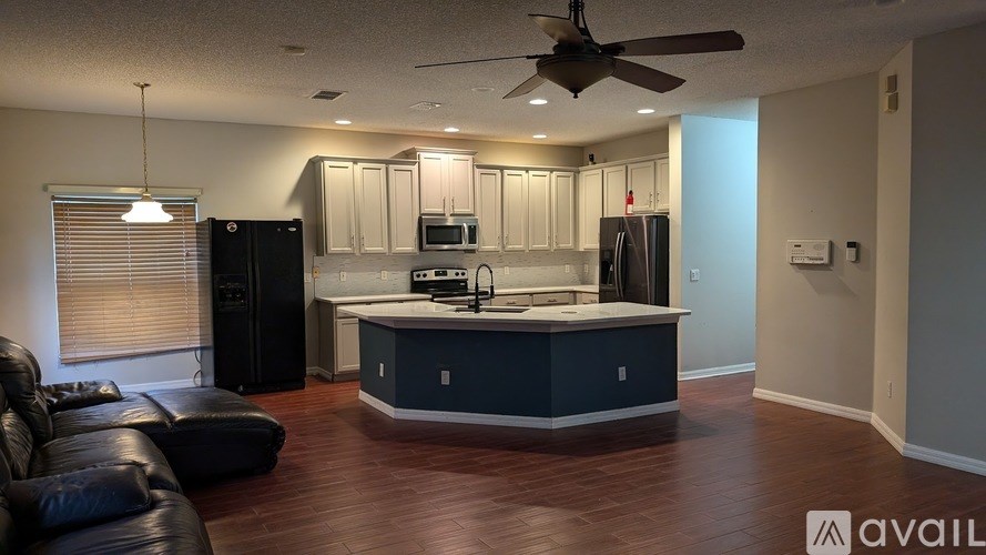 A kitchen with a black fridge and a black leather couch.