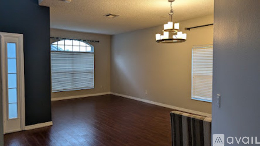 A room with a chandelier, a window with blinds, and a radiator on the floor.