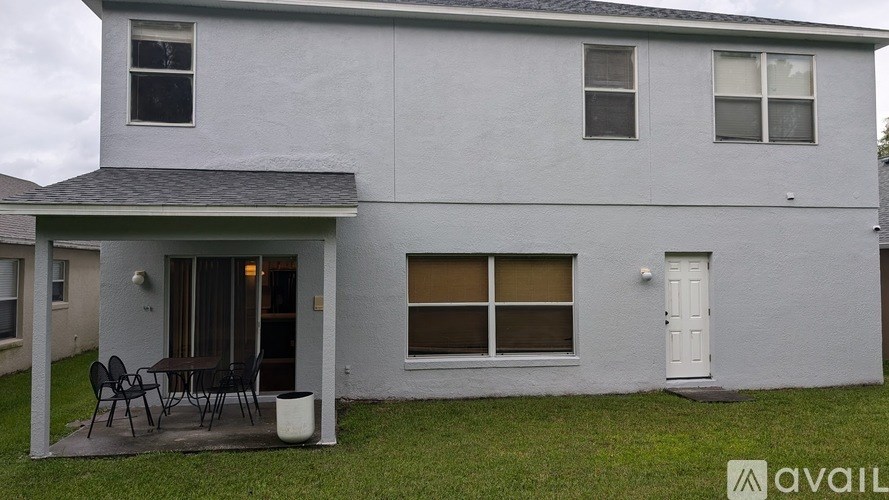 A grey house with a patio and chairs.