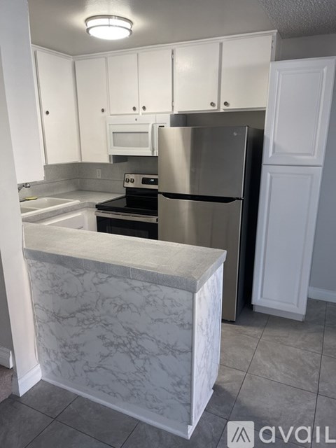A kitchen with a marble island and stainless steel appliances.