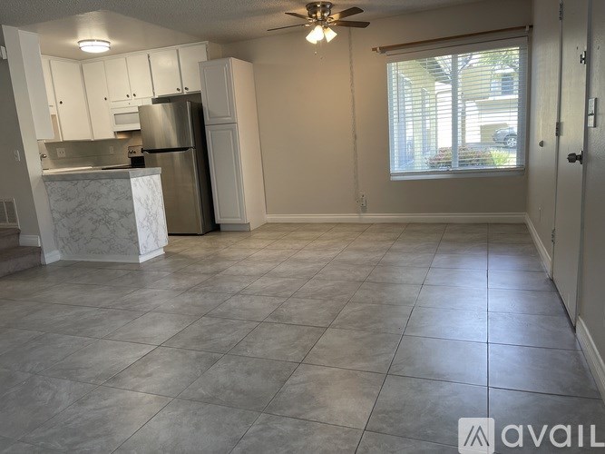 A kitchen with a refrigerator, cabinets, and a ceiling fan.