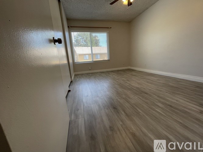 A room with a wooden floor and a window with blinds.