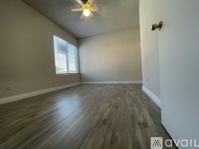 A room with a ceiling fan and wooden flooring.