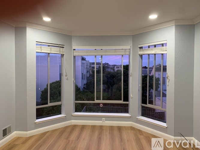 A room with a large window and wooden flooring.