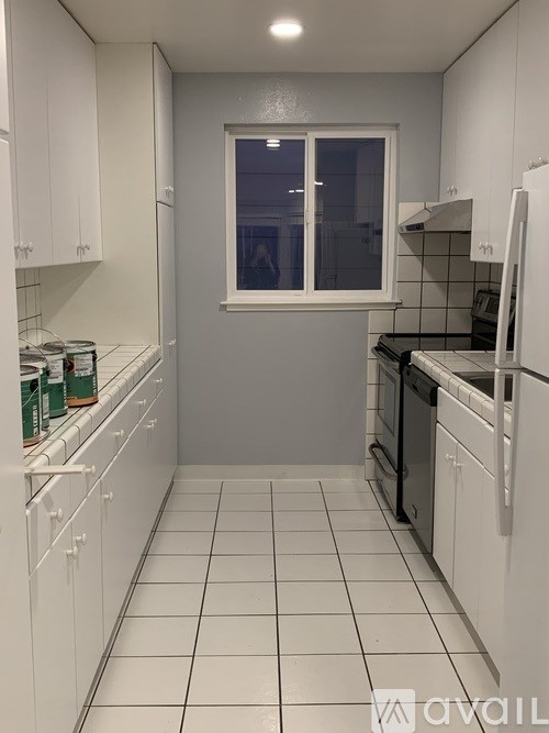A kitchen with white cabinets and black appliances.