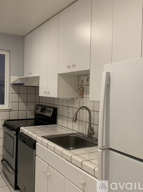 A kitchen with white cabinets and black appliances.