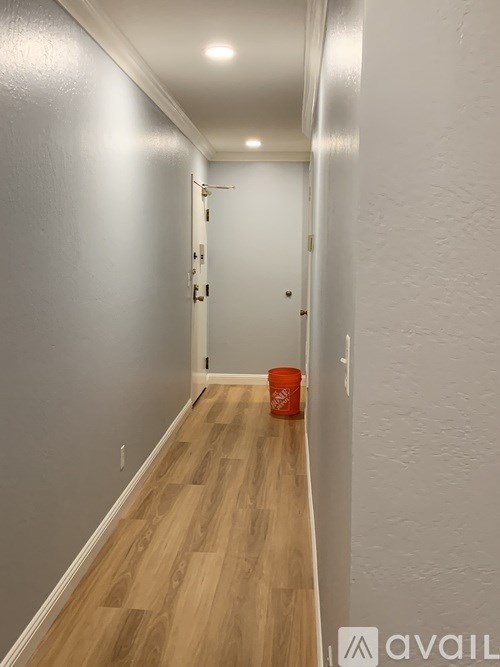 A long hallway with wood floors and white walls.