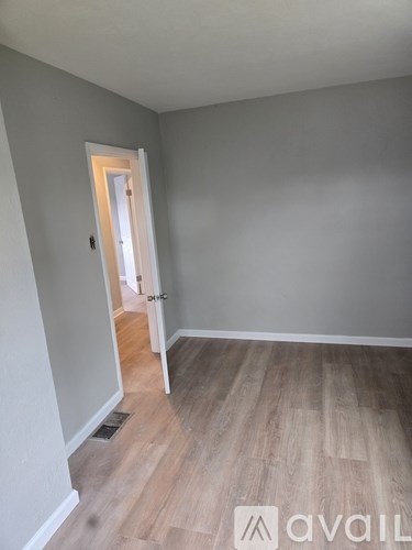 A room with a wooden floor and a door leading to another room.