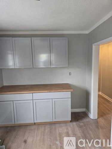 A kitchen with white cabinets and a wooden countertop.