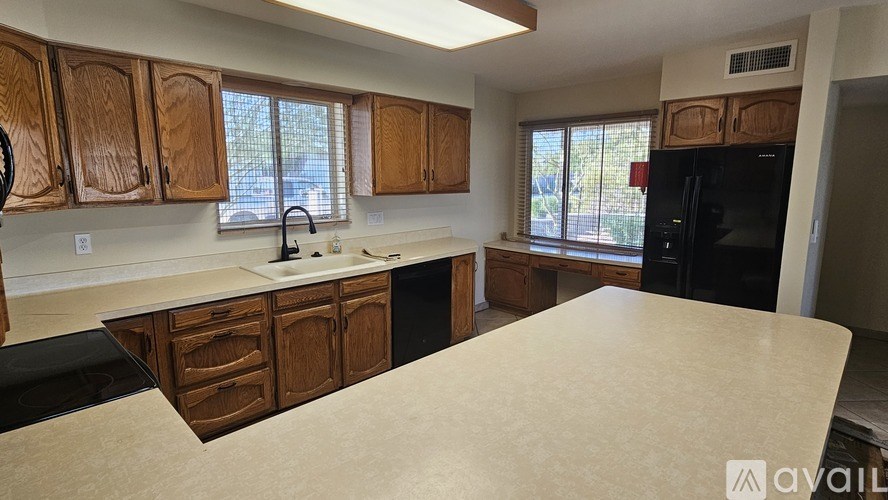 A kitchen with wooden cabinets and a black refrigerator.