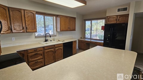 A kitchen with wooden cabinets and a black refrigerator.