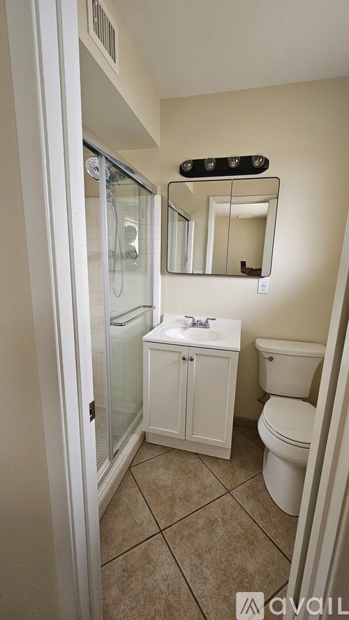 A bathroom with a toilet, sink, and mirror.