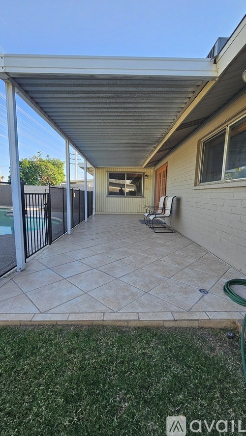 A patio with a table and chairs is covered by a roof.