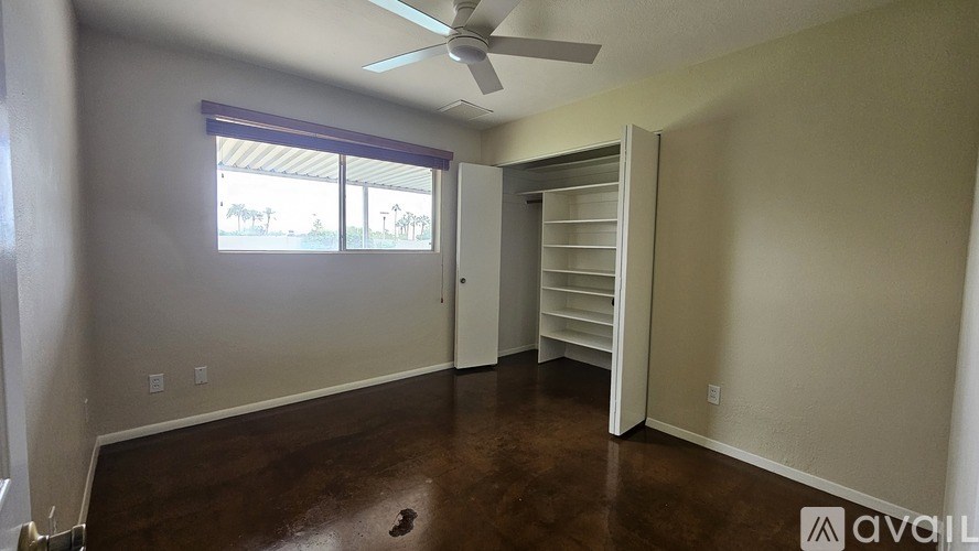 A room with a ceiling fan and a window with blinds.