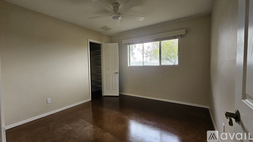 A room with a brown floor and a ceiling fan.
