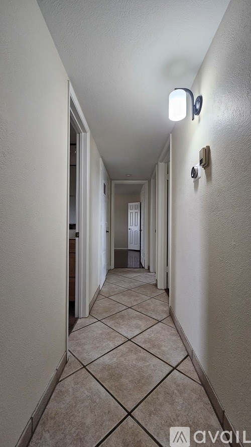 A long hallway with tiled floors and white walls.