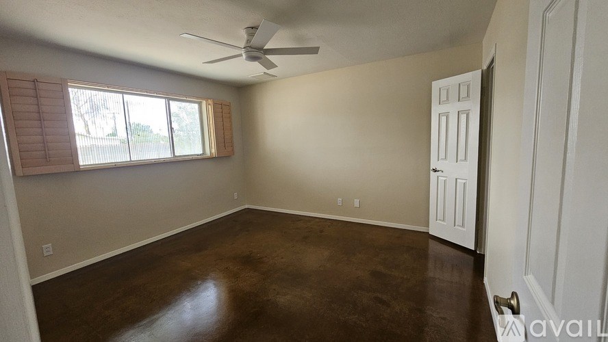 A room with brown flooring and a ceiling fan.