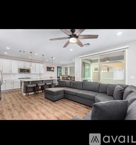 A modern living room with a grey sofa and a kitchen area in the background.