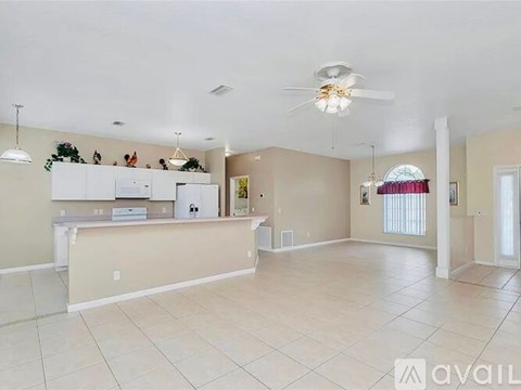 A spacious kitchen and living room with a white refrigerator and a ceiling fan.