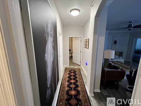 A hallway with a rug on the floor and a painting on the wall.